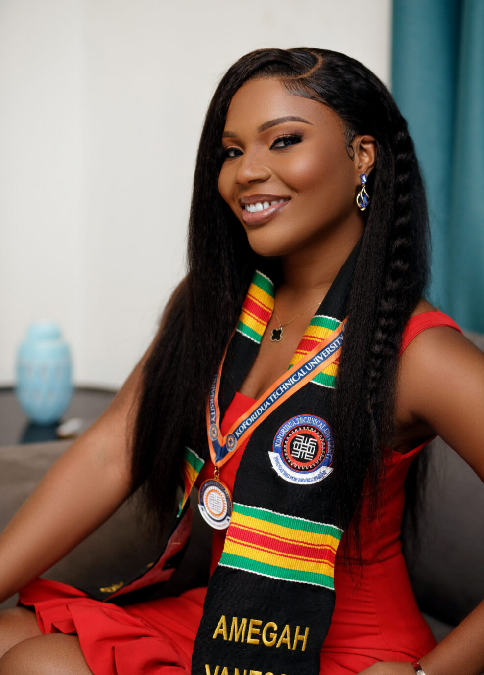 Graduate in red dress wearing a black authentic Kente Graduation Stole