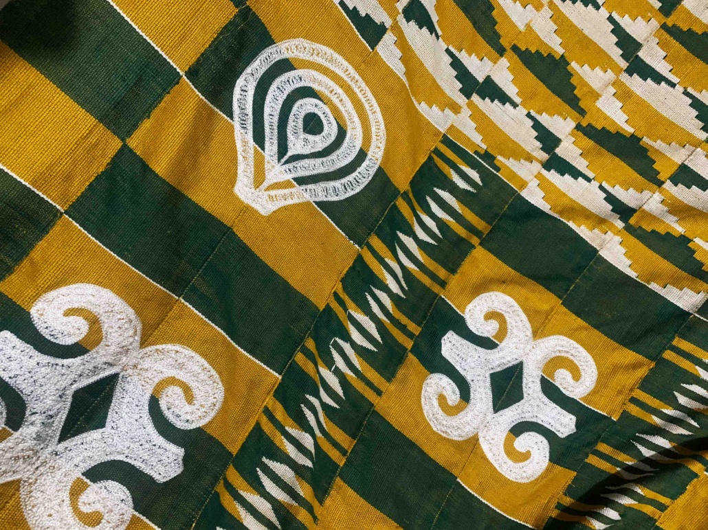 Green and gold Kente fabric with white hand embroidery